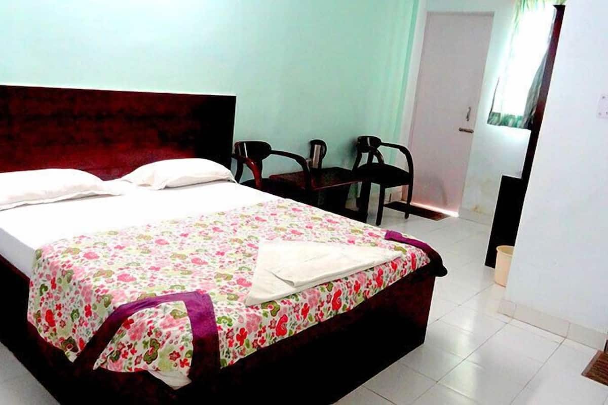 A bedroom with a bed, a desk, and a chair.