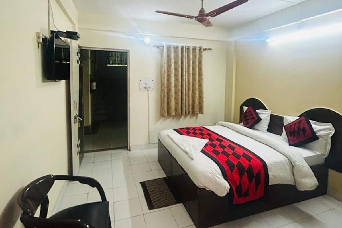 A bedroom with a bed, a ceiling fan, a door, and a chair.