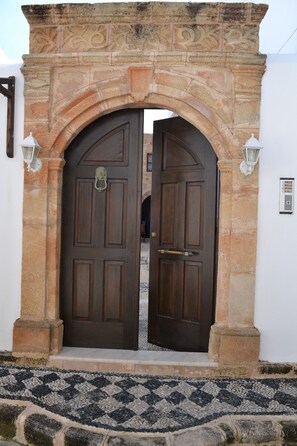 Traditional entrance with a stone archway, flanked by wall-mounted lanterns, leading to a welcoming door.