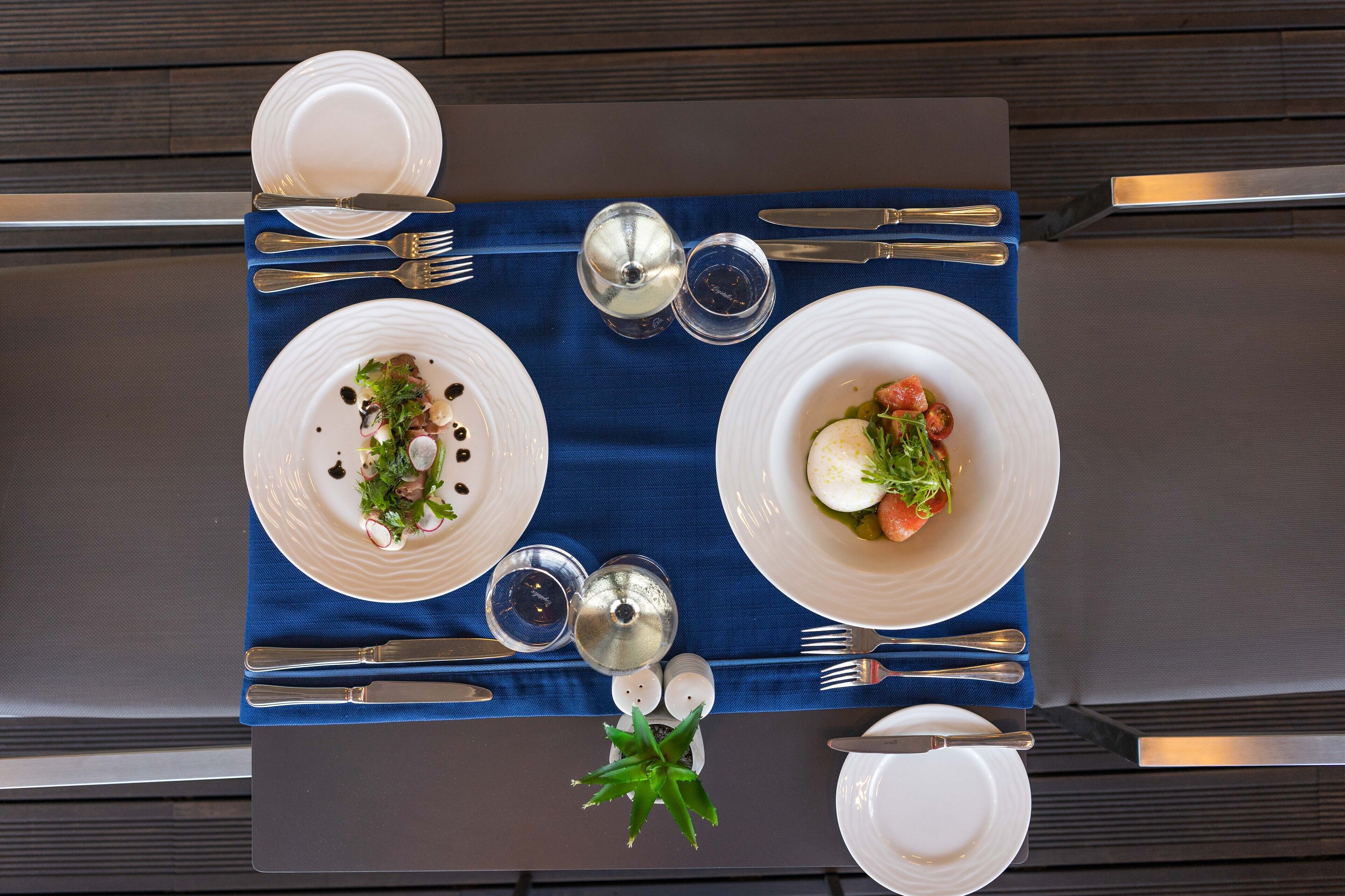 A table set with plates of food, cutlery, and salt and pepper shakers.