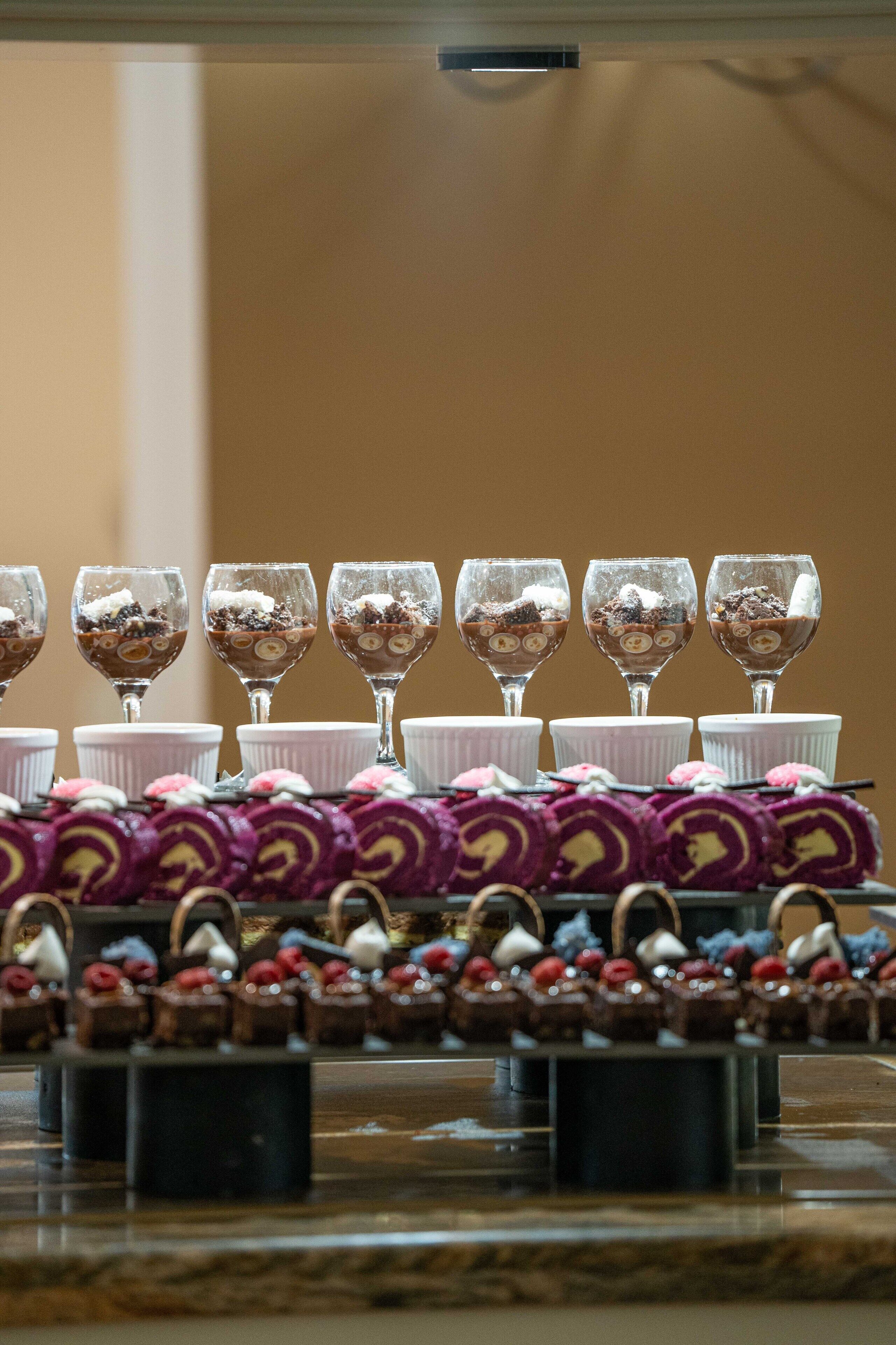 Una exhibición de postres con diversos dulces y vasos de una bebida.