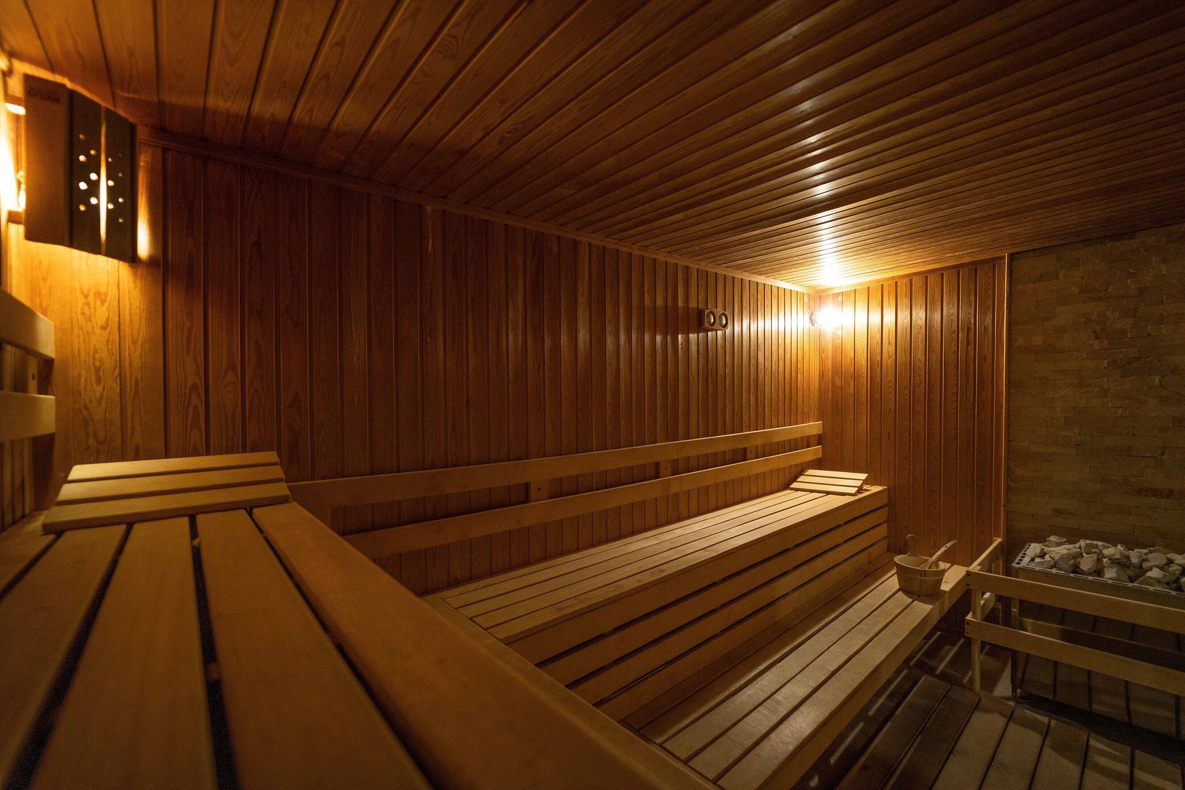 Una sauna con bancos de madera y pared de piedra.