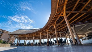 An open-air pavilion with a curved roof supported by wooden beams, surrounded by outdoor seating and a view of the sky. - HVD Club Hotel Miramar - Ultra All Inclusive (Obzor)