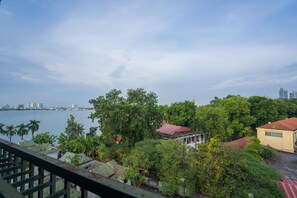 A coastal view with a building surrounded by dense greenery and a body of water. - Coco Flower Village Serviced Apartment (Hanoi)