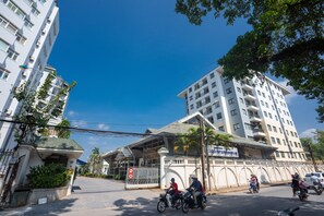A multi-story building with balconies, a gated entrance, and a clear blue sky. - Coco Flower Village Serviced Apartment (Hanoi)