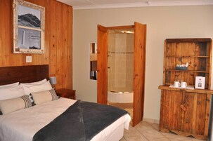 Un dormitorio con cama, un armario de madera, un cuadro enmarco y una zona de ducha.