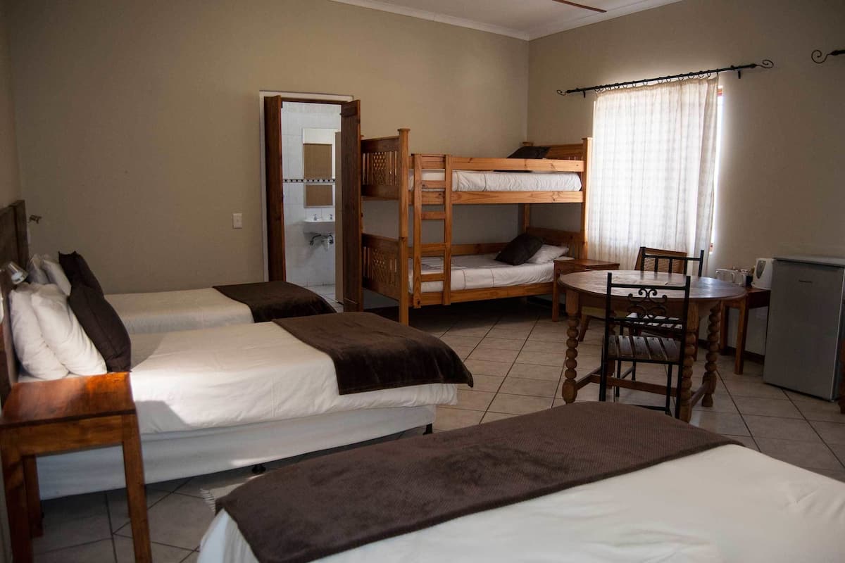 Une chambre avec des lits superposés, une petite table, des chaises et un réfrigérateur.