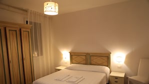 A hotel room with a bed, two bedside tables, a chair, a wardrobe, and a hanging light fixture. - Lovely Apartment In Venice (Venice)
