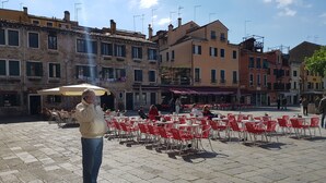 A courtyard with outdoor seating, stone paving, and historic buildings in the background. - Lovely Apartment In Venice (Venice)