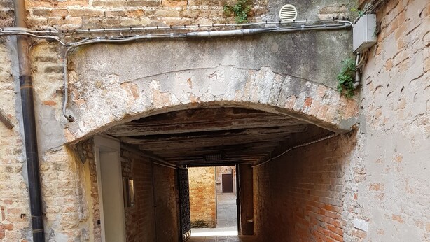 A narrow stone pathway leading to a doorway under a brick archway. - Lovely Apartment In Venice (Venice)