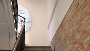 A staircase with a wooden handrail, a brick wall, and a white ceiling. - Lovely Apartment In Venice (Venice)