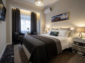 A hotel room with a bed, bedside tables, a TV, a painting, and a window with curtains. - Siliahouse (Naples)