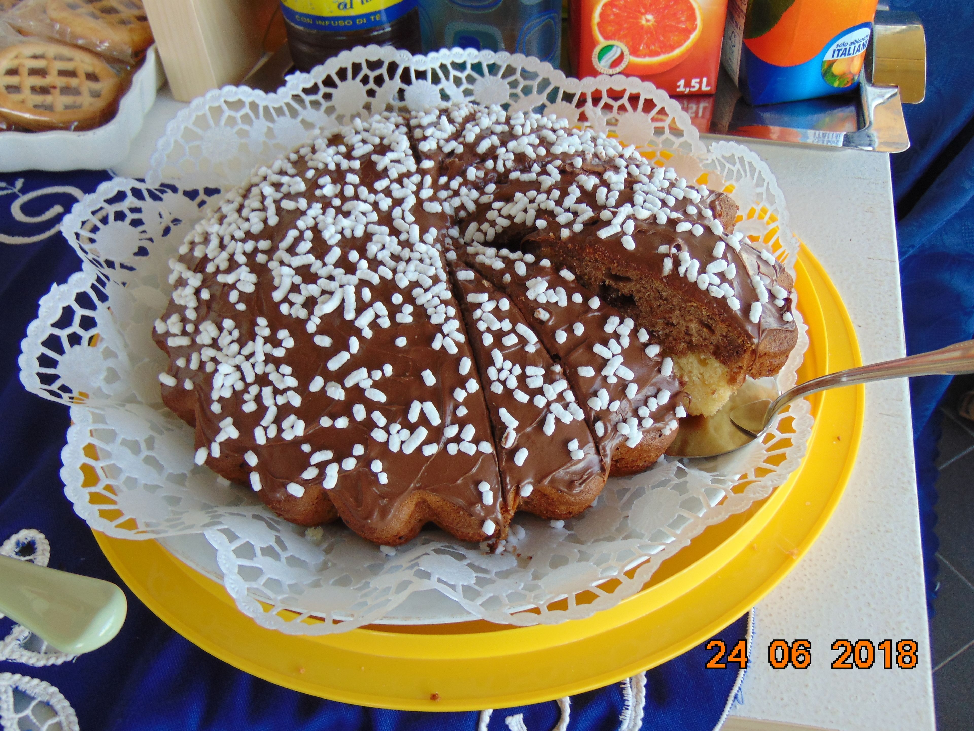 A chocolate-covered cake with white sprinkles on a yellow plate, placed on a lace doily.