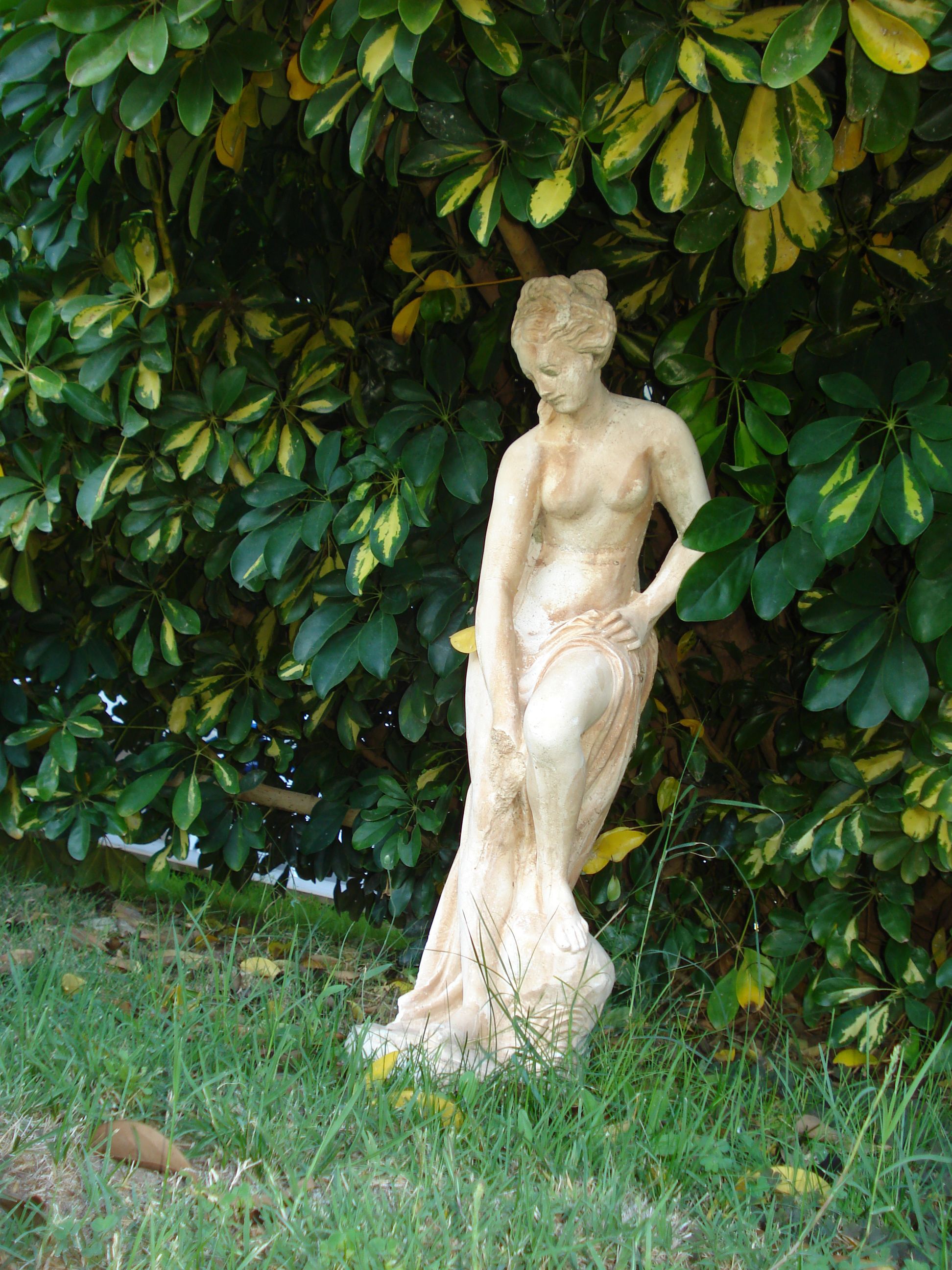 Eine Statue einer Frau in einer Gartenanlage.