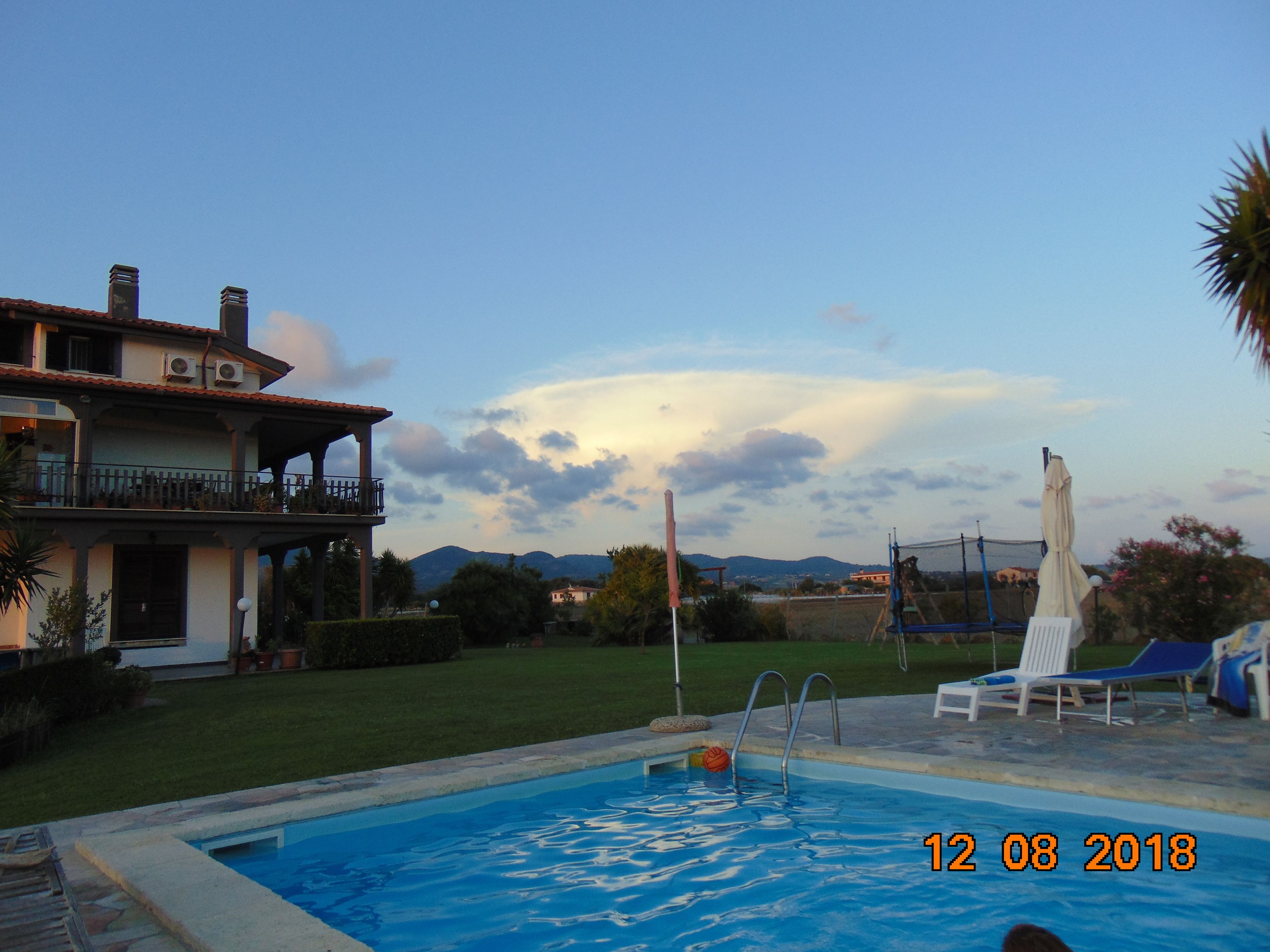 A swimming pool with a view of a house and mountains in the background.