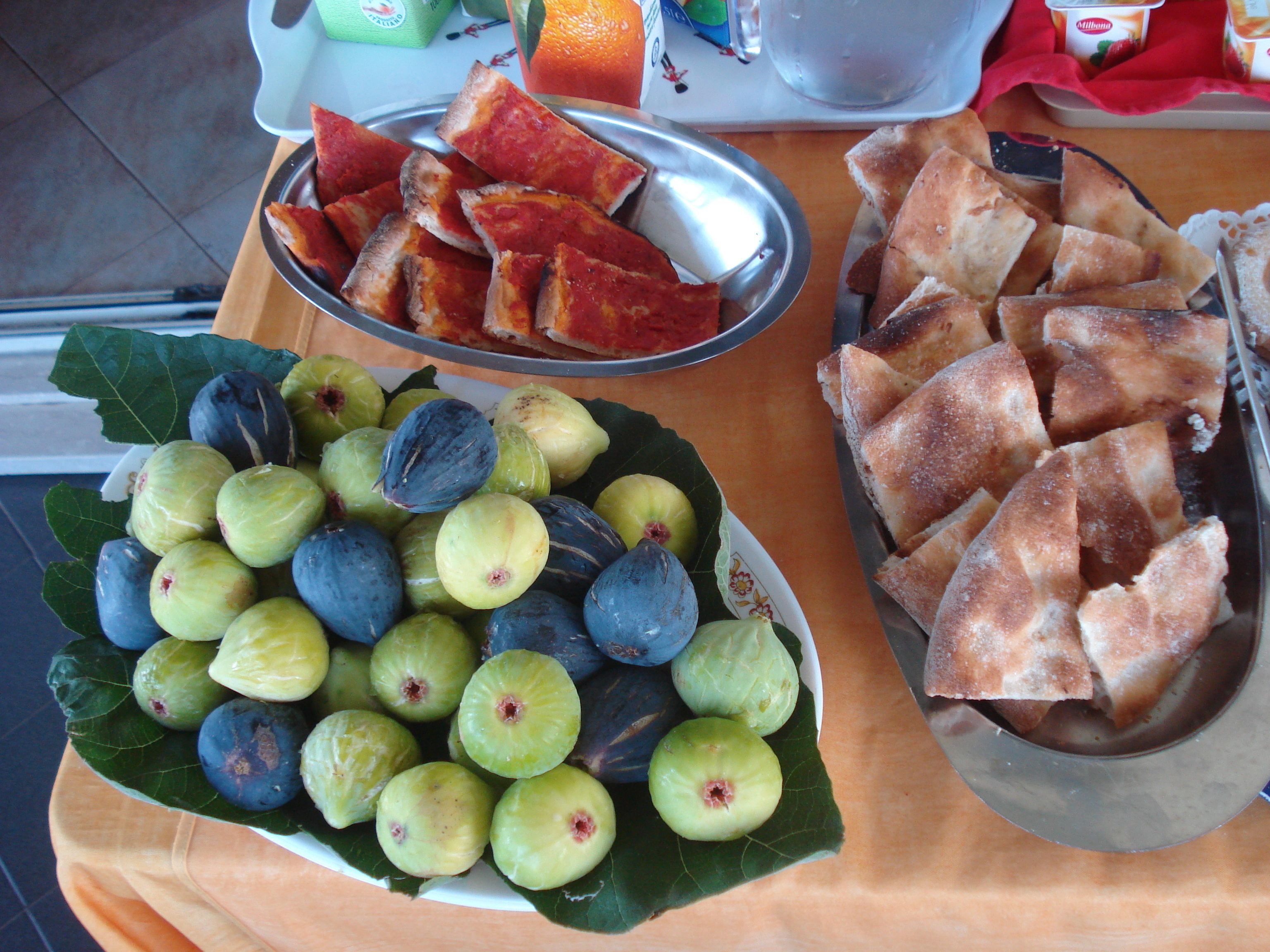 A table with a variety of food items including sliced bread, figs, and oranges.