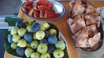 A table with a variety of food items including sliced bread, figs, and oranges.