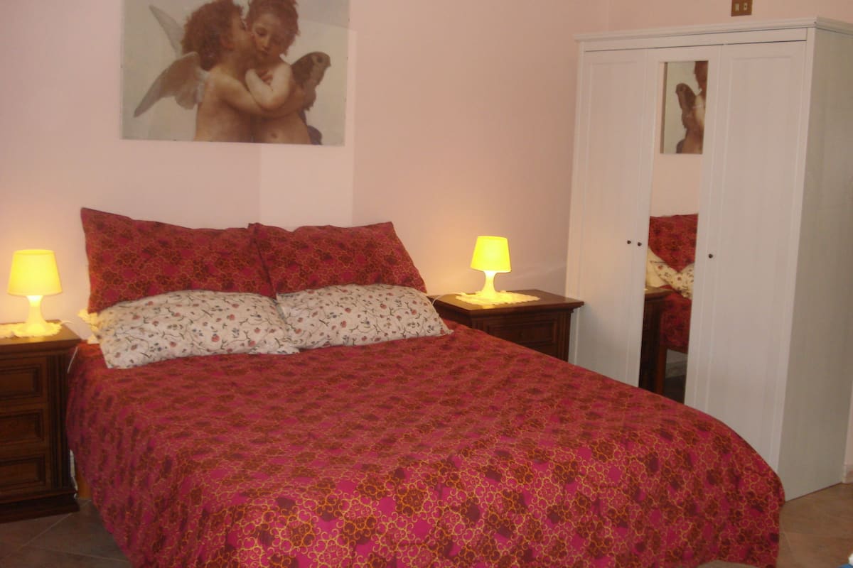 Une chambre à coucher avec un grand lit, deux lampes de chevet, un miroir et une porte.