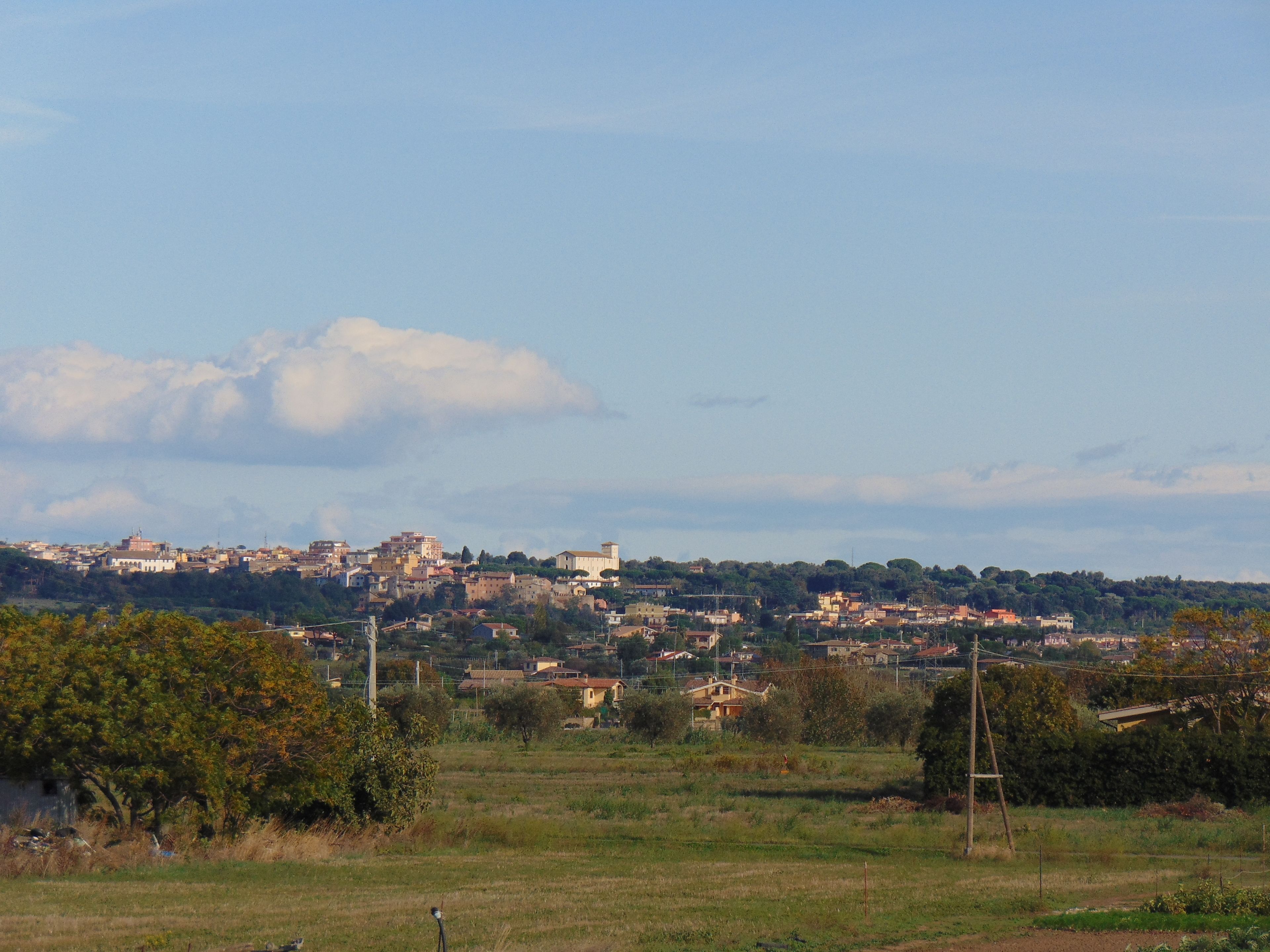 A panoramic view of a town with buildings spread across a hilly landscape.