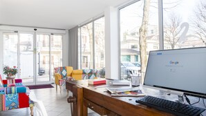 A modern office space with a wooden desk, a computer, and a colorful sofa. - Residence Cigno (Rimini)