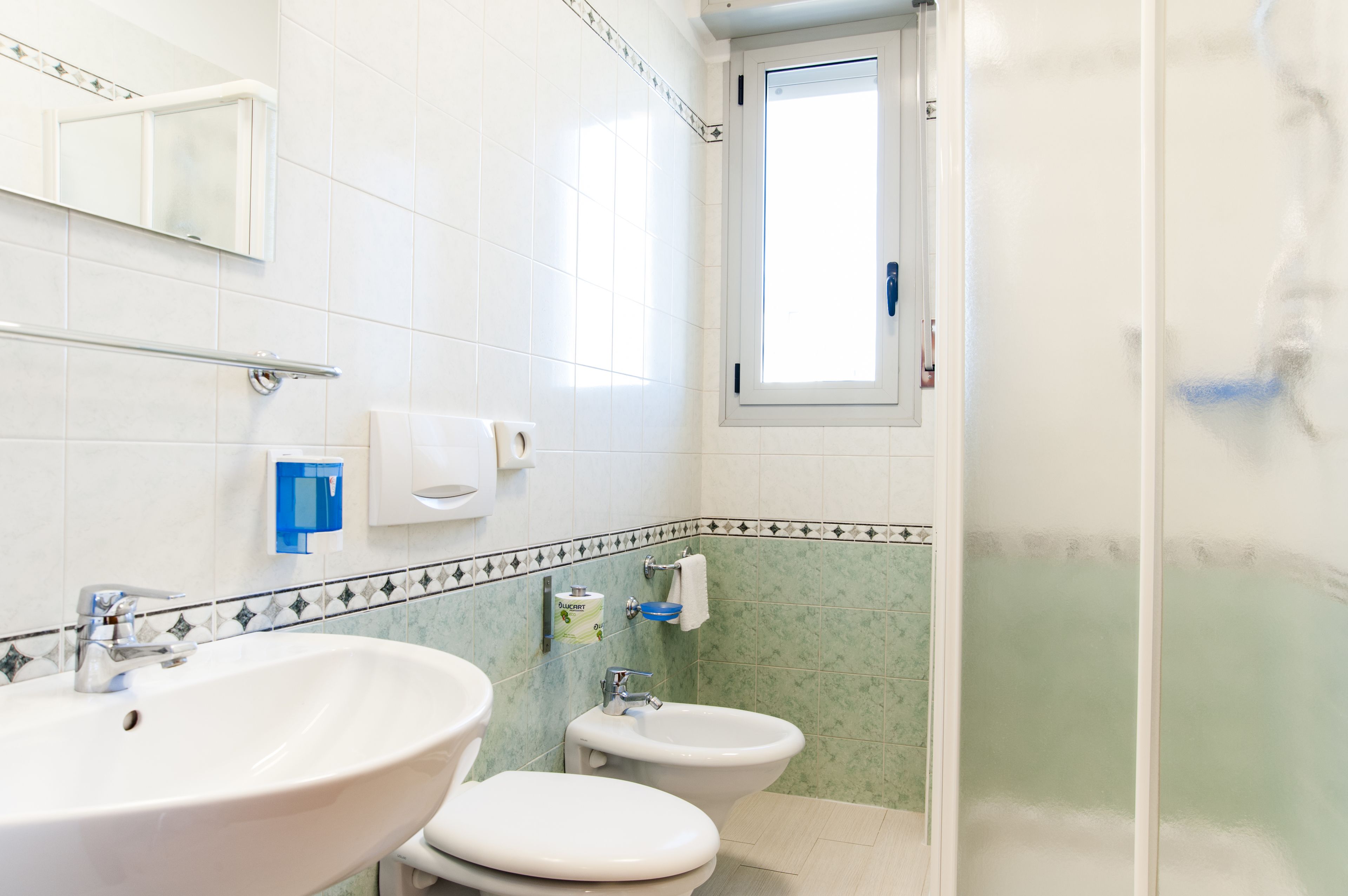 A bathroom with two sinks, a bidet, and a mirror.