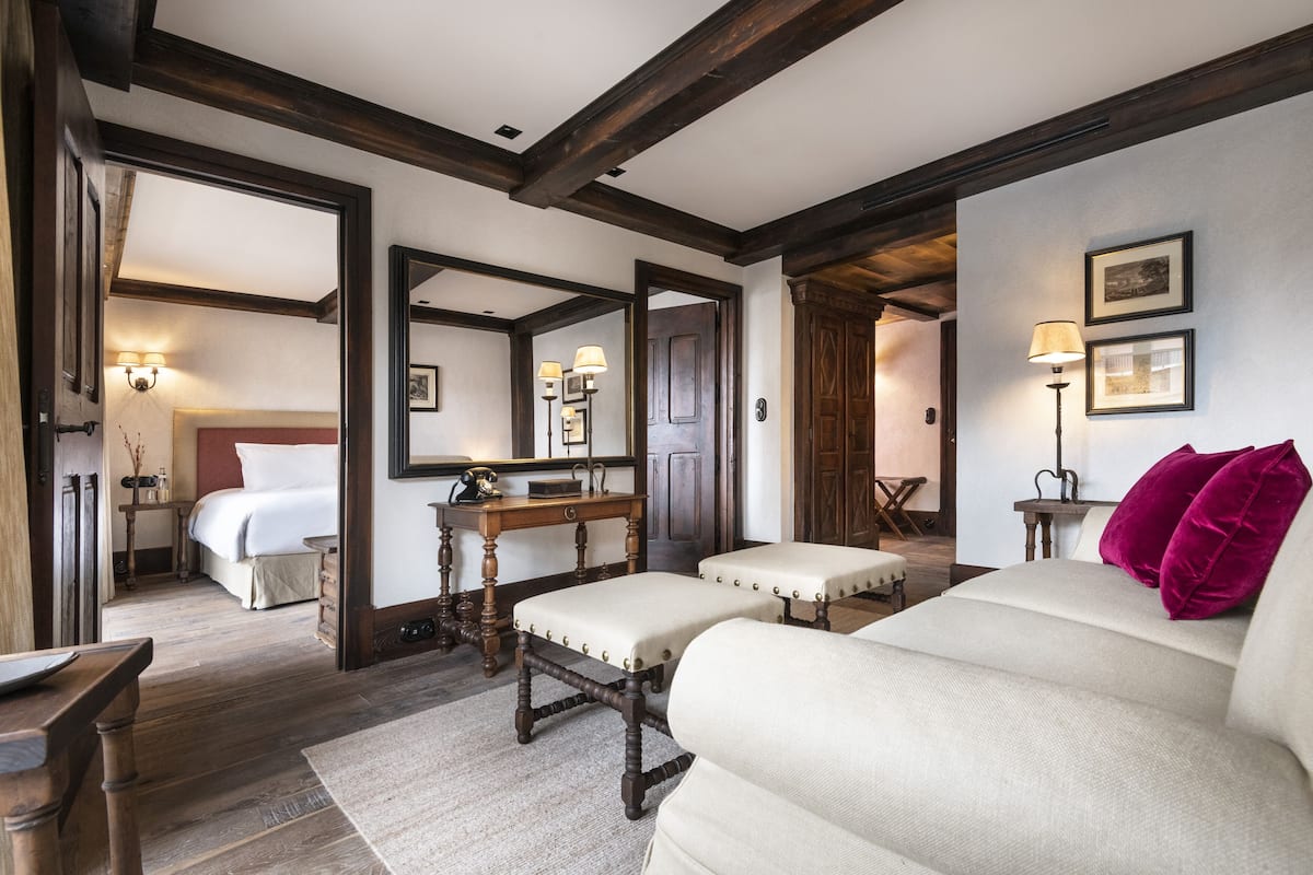 A traditional room with a bed, a sofa, a wooden bench, and a desk with a lamp.