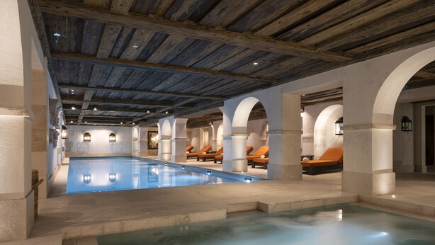 A large indoor swimming pool with multiple lounge areas and a rustic wooden ceiling. - Airelles Val d’Isère , Le Brussel's (Val-d'Isere)