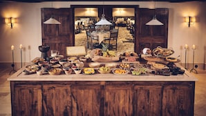 A large wooden island with a variety of food items and a view into a dining area with tables and chairs. - Airelles Val d’Isère , Le Brussel's (Val-d'Isere)
