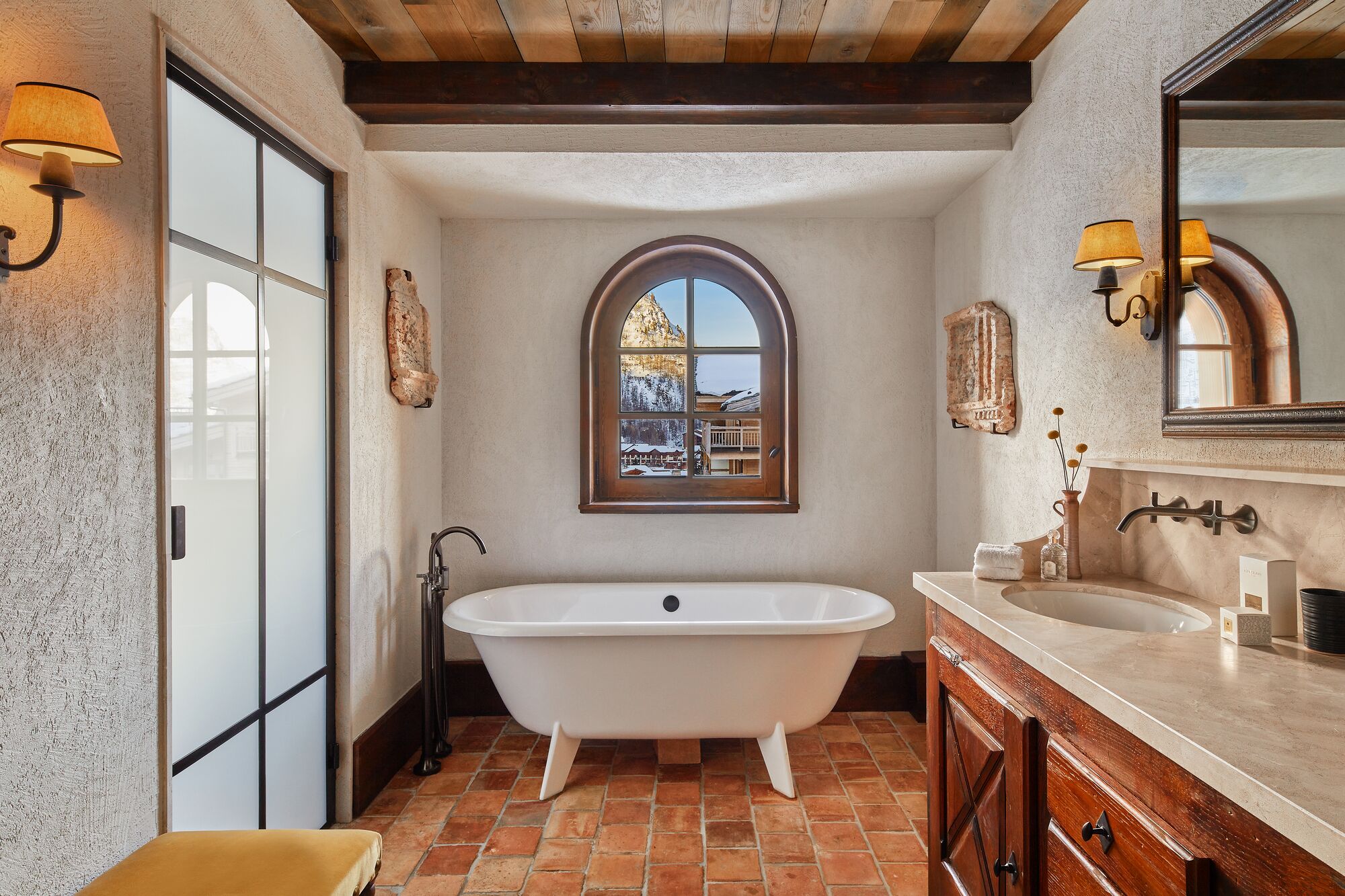 A bathroom with a freestanding bathtub, a sink, and a large mirror.