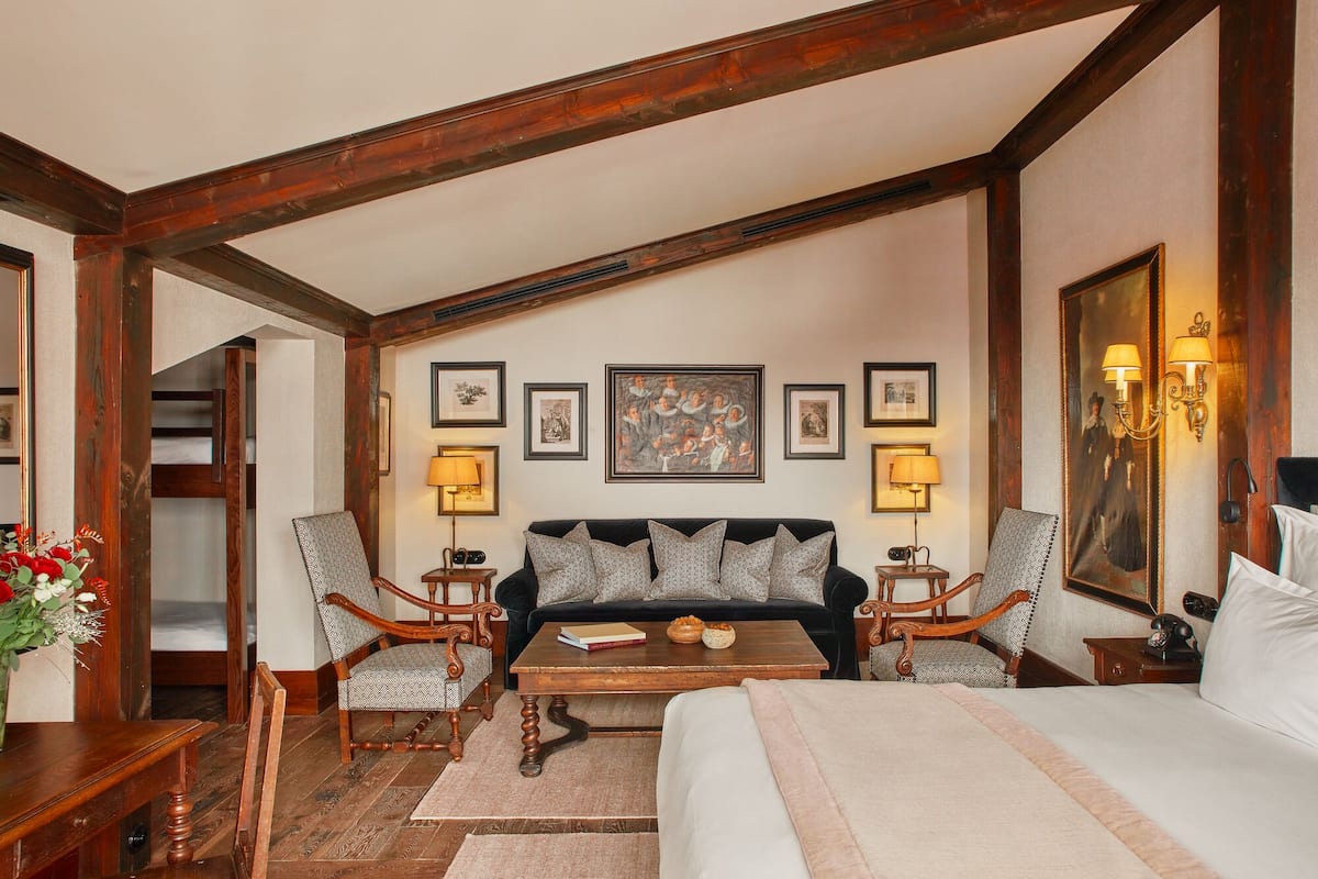 A cozy room with a wooden ceiling, a sofa set, a coffee table, and framed artwork on the walls.