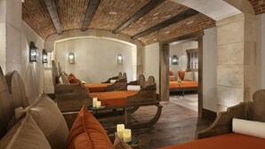 A spa room with wooden benches and orange cushions, a brick ceiling, and a stone wall. - Airelles Val d’Isère , Le Brussel's (Val-d'Isere)