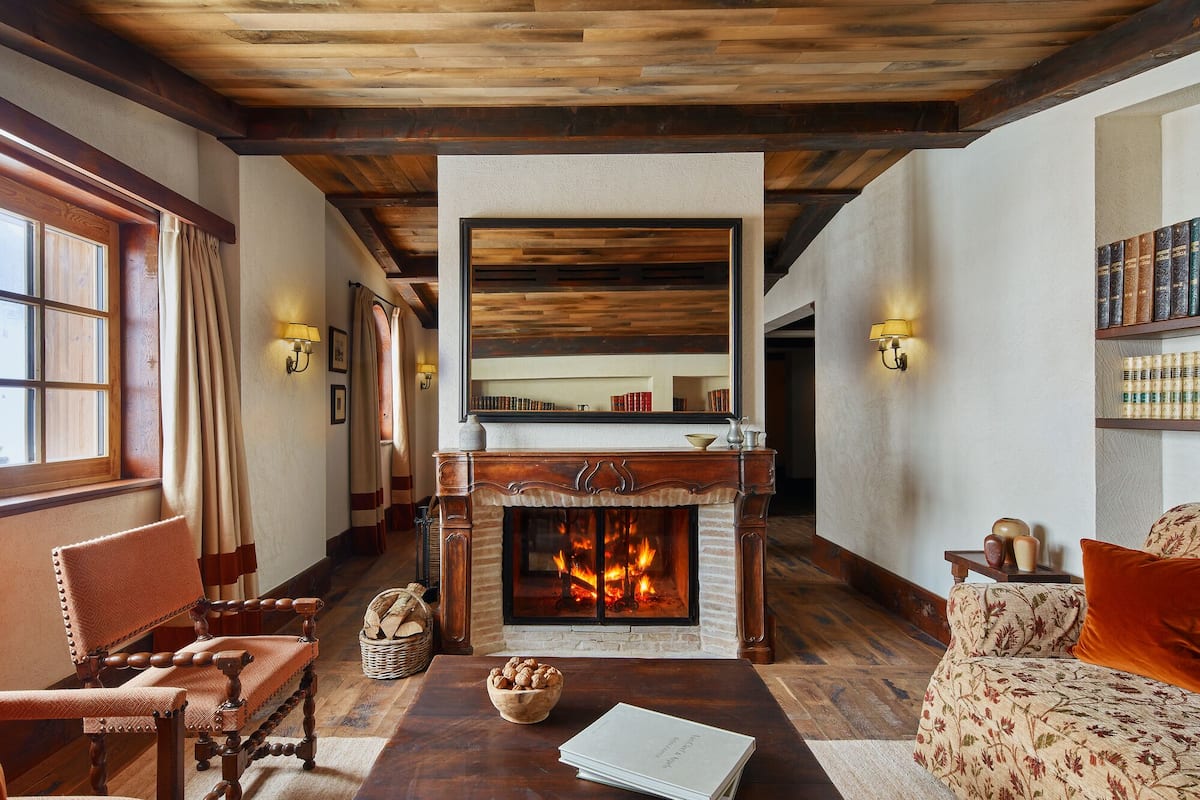 A cozy living room with a fireplace, wooden furniture, and bookshelves.