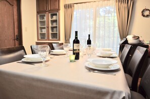Une table à manger dressée avec des assiettes, des verres et des bouteilles de vin, entourée de chaises.