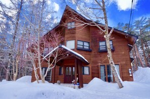 Une cabane en bois entourée d’arbres couverts de neige.