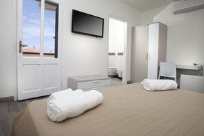 Habitación de hotel con cama, televisión, armario, escritorio y silla.