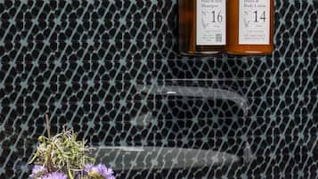 A bathroom with a patterned wall, a white bathtub, and two bottles of shampoo and lotion.