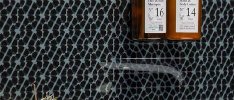 A bathroom with a patterned wall, a white bathtub, and two bottles of shampoo and lotion.