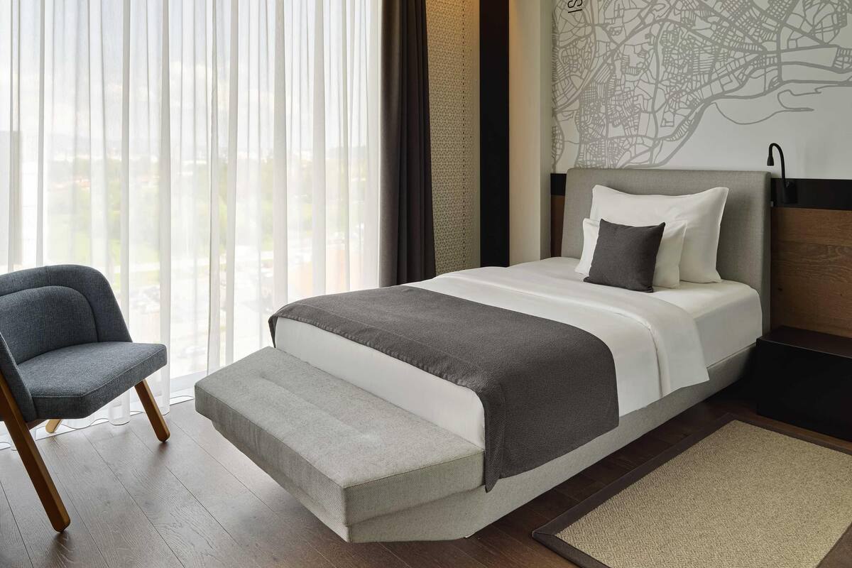 Een moderne hotelkamer met een groot bed, een fauteuil en een stadskaart aan de muur.