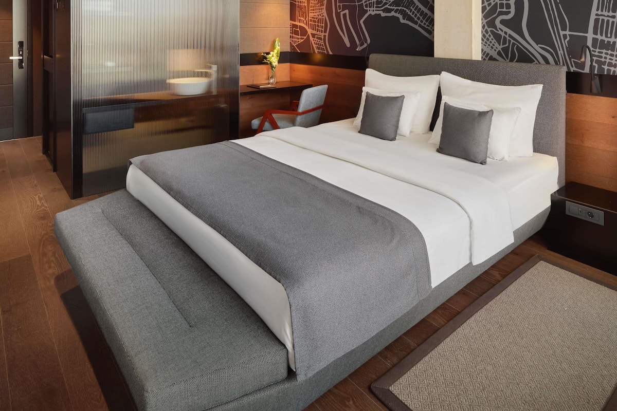 Een moderne hotelkamer met een groot bed, een bureau en een stoel.