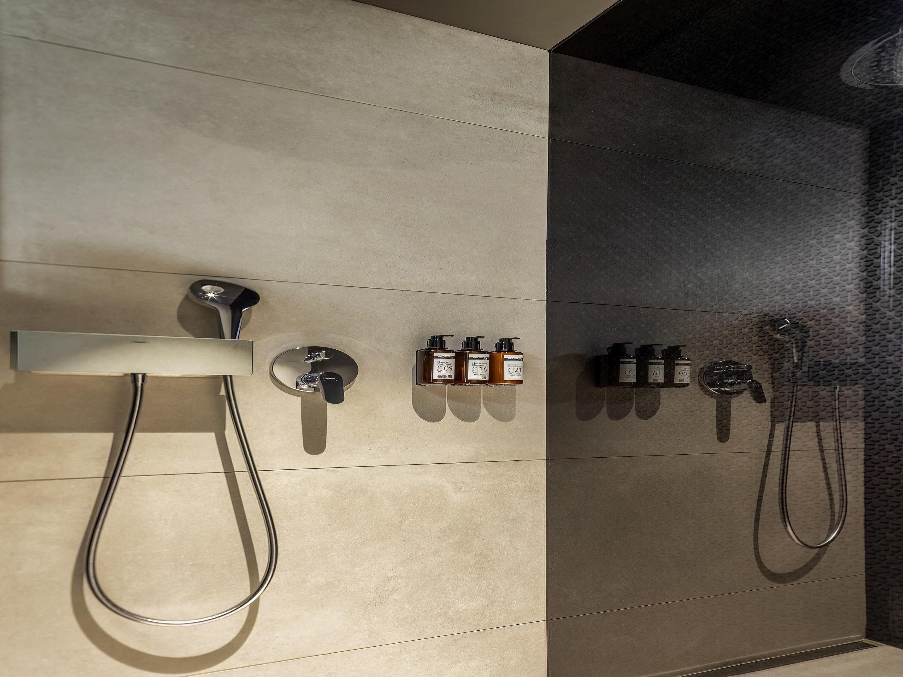 A modern shower area with a handheld showerhead, a wall-mounted faucet, and a series of toiletries.