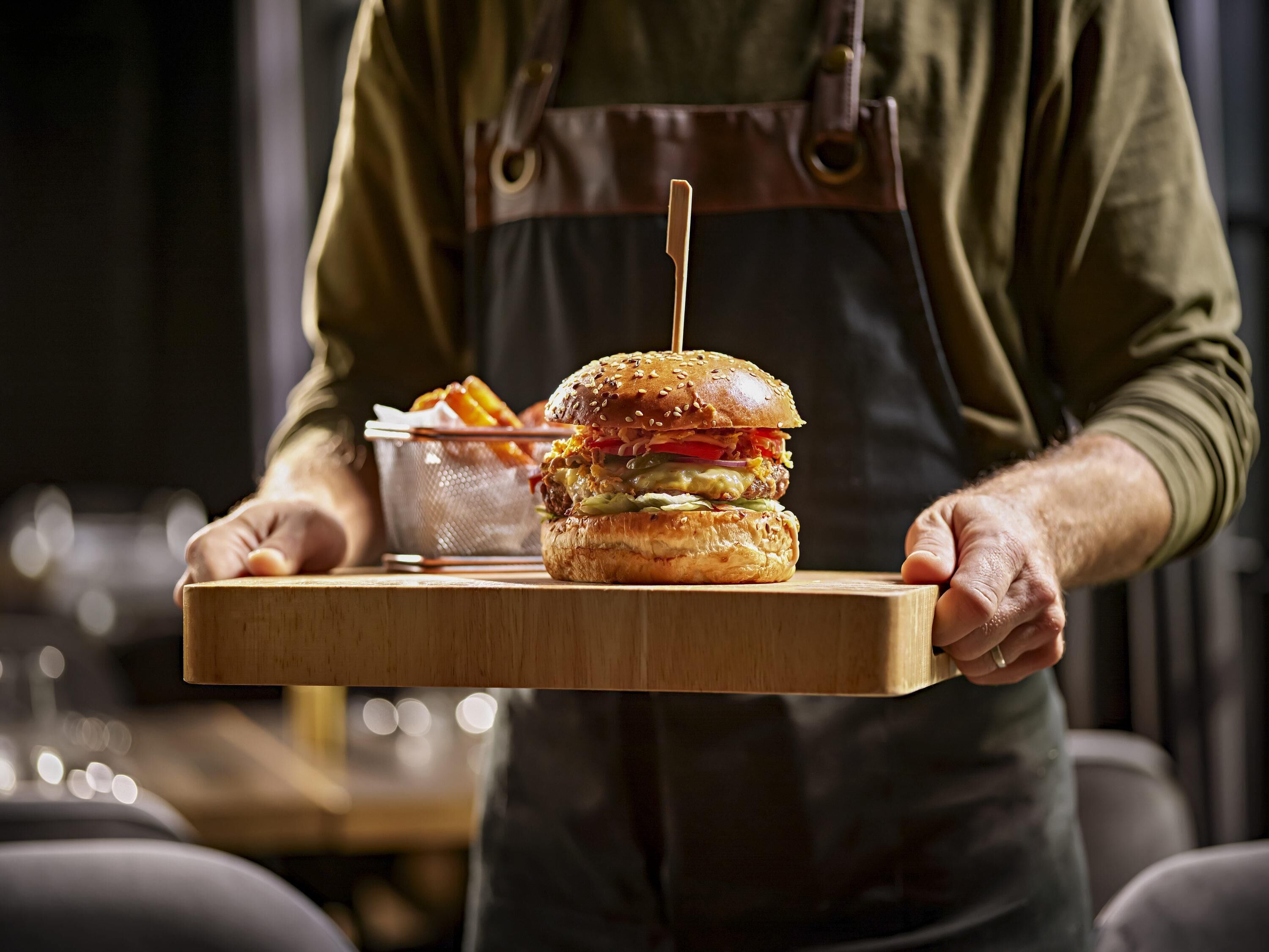 A person holding a tray with a burger and fries.