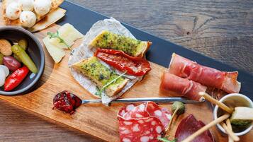 A wooden board with various food items including bread, cheese, and cured meats.