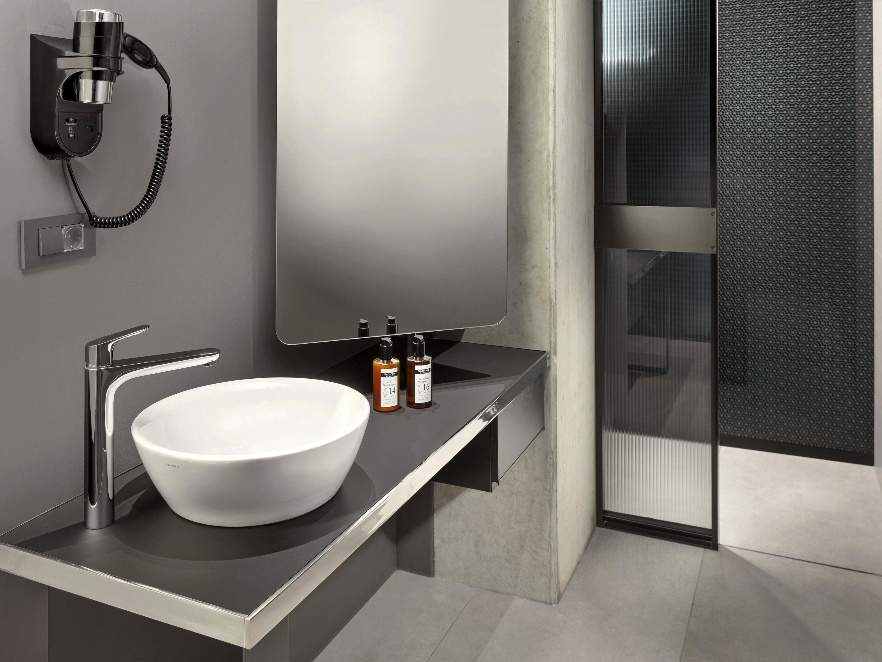 A modern bathroom with a large white sink, chrome fixtures, and a mirror.