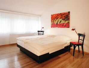 A bedroom with a bed, a chair, a desk, and a painting on the wall. - Hotel Schlafschön (Hann. Muenden)