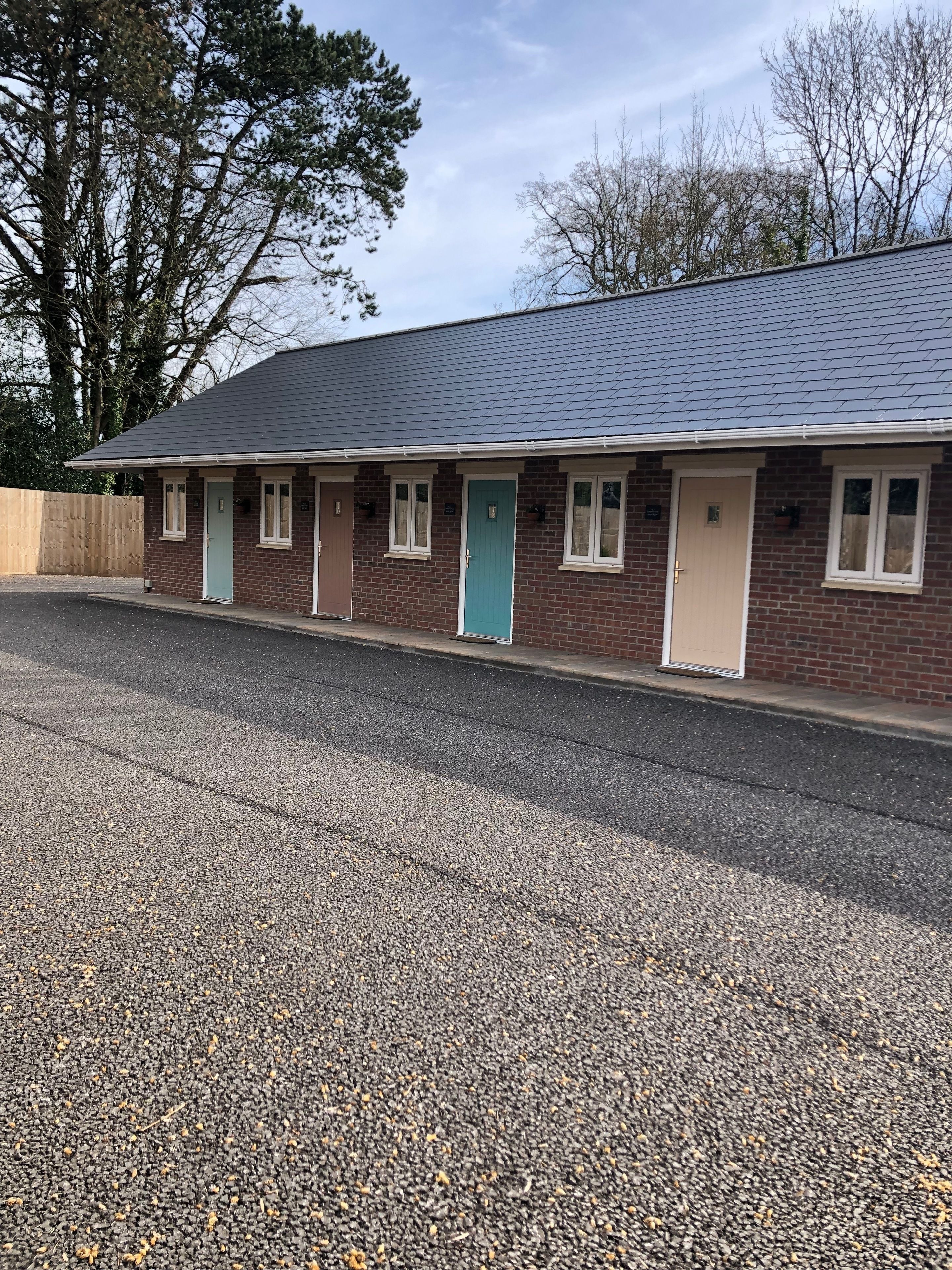 A row of single-story brick buildings with a gravel driveway.