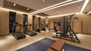 Une salle de sport moderne équipée de tapis de course, de vélos elliptiques et d’appareils de musculation.