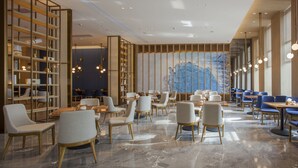 Un restaurant moderne doté d’un sol en marbre, de meubles en bois et d’une grande fresque bleue sur le mur du fond.