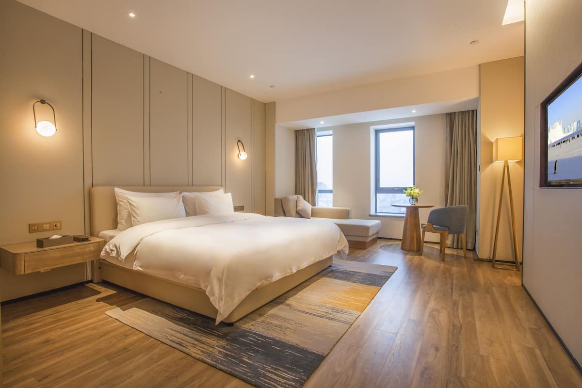 Une chambre d’hôtel moderne avec un grand lit, des tables de chevet, un bureau et une chaise.