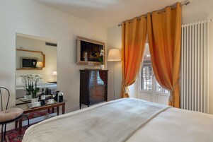 Una habitación de hotel con cama, escritorio con lámpara, cómoda y espejo.