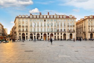 A large public square with historic buildings, including a bank and a café.